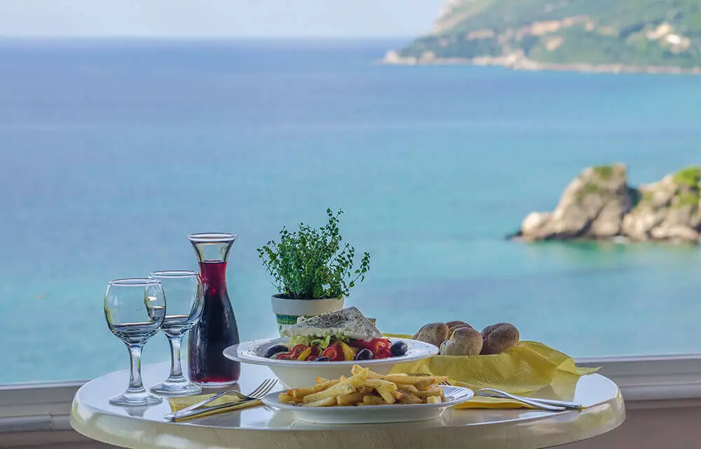 Μεσημεριανό στη βεράντα: σαλάτα, κρασί και ψωμί, με τη θάλασσα από κάτω