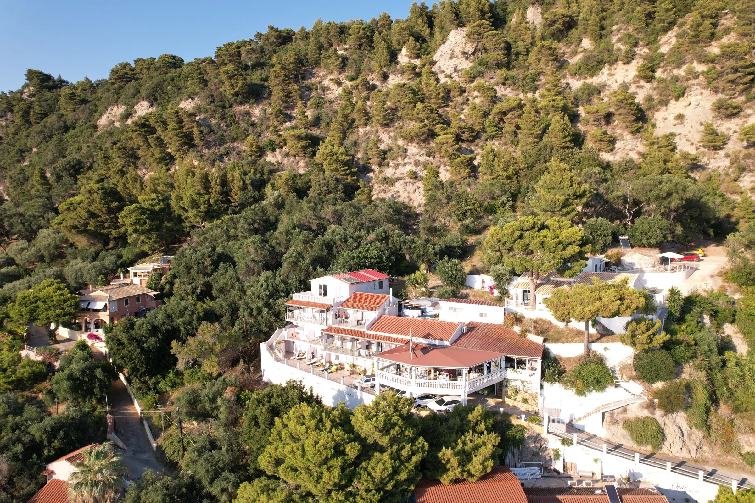 Το Bella Vista ανάμεσα στα δέντρα της πλαγιάς, πάνω από τον κόλπο